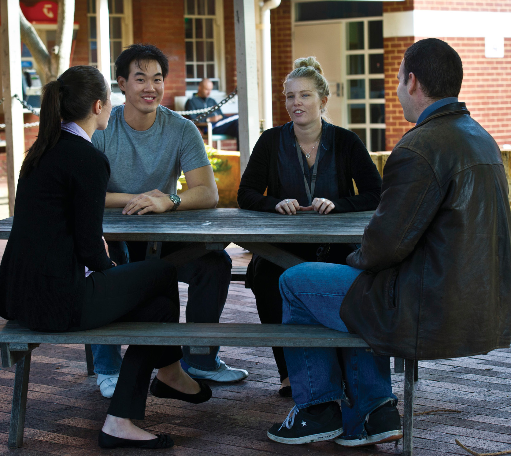 4 people sitting around a picnic table talking